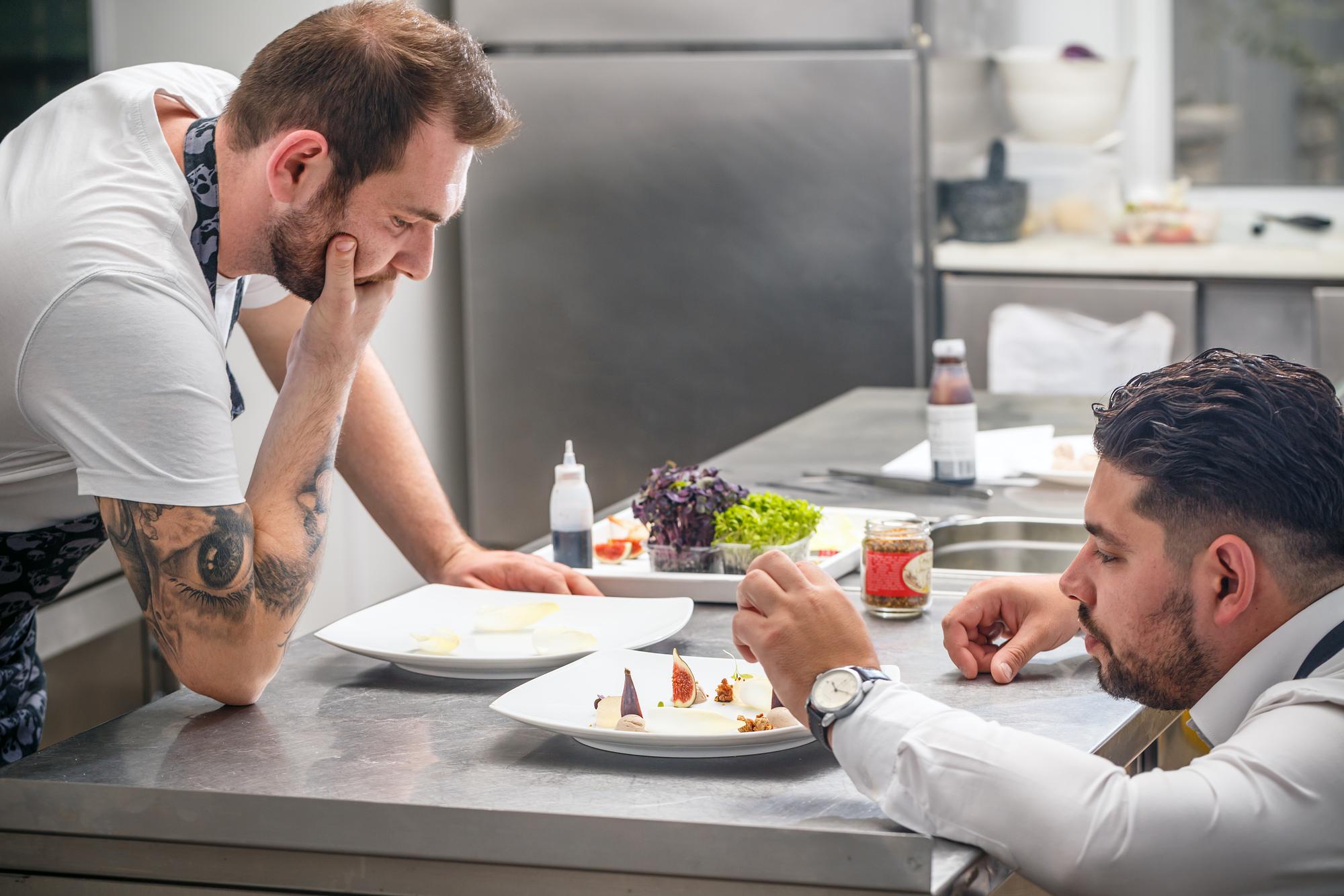 consultant with chef discussing plating in modern kitchen